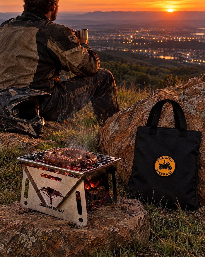 Die Bonsai Braai met 'n worsrol op die rooster teen sononder, langs die Proudly Meerkat-seilsak.