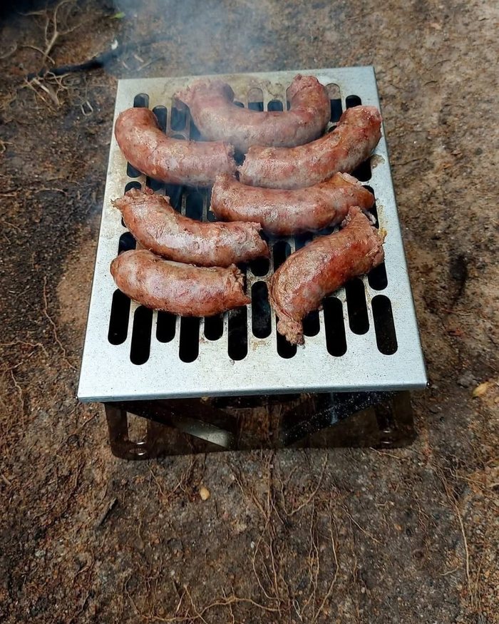 Boerewors wat op die Bonsai Braai se rooster braai, met die kole wat onder deurskyn.