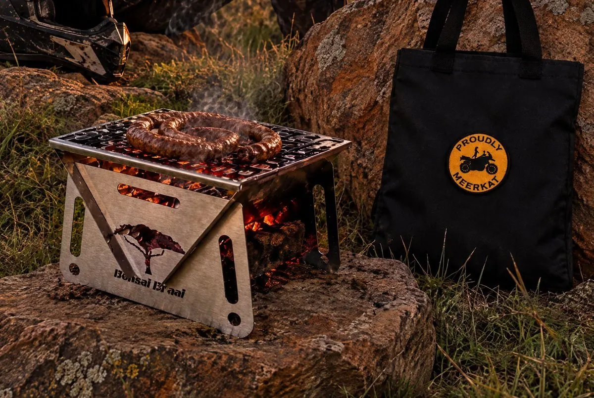 The Bonsai Braai on a rock with coals glowing, canvas bag beside it